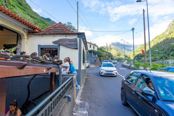 exterior of the typical poncha tavern with customers consuming drinks and eating peanuts with the shells on the ground, Madeira island.