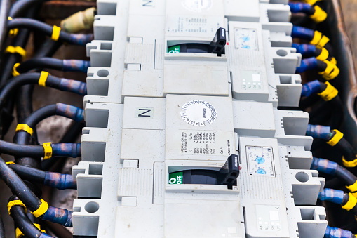 Electric cables connected to a distribution block with switches, close-up.