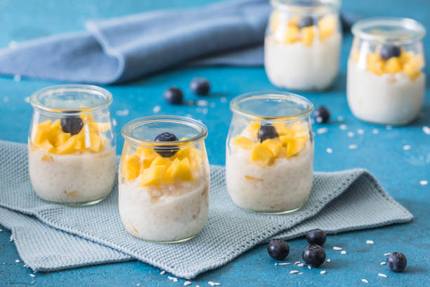 istock Coconut rice pudding with mango in dessert glasses on blue background 1486885191