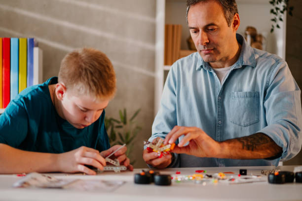 istock Father helping his son while putting together a toy and enjoying at home. 1486886366