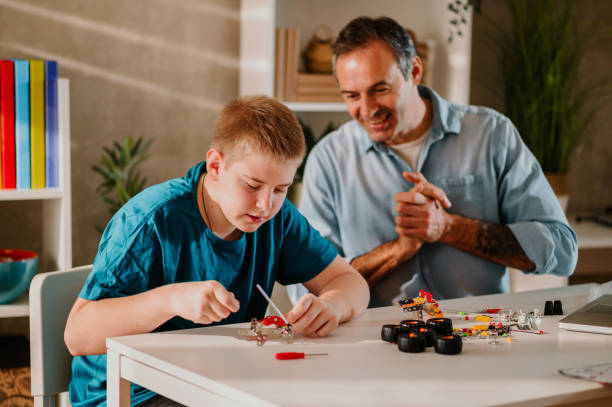 istock Blond young boy assembling his toy patiently while his dad is watching with joy. 1486886374