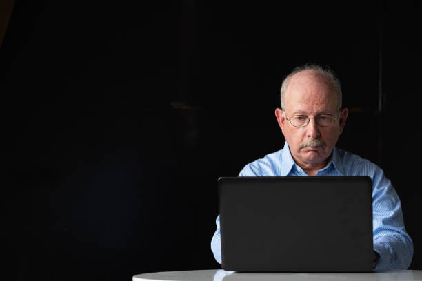 istock Grey haired senior man with mustache wearing eyeglasses and using laptop computer 1486887991