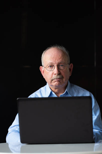istock Grey haired senior man with mustache wearing eyeglasses and using laptop computer 1486887999