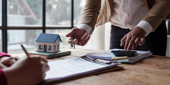 Close up Business people or Real Estate agent explain signing agreement for sale house to client. Property, Insurance, Broker concept.