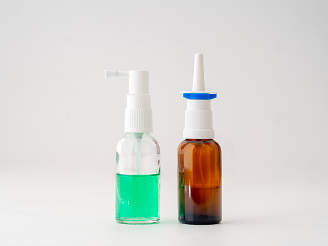 Two glass bottles of nasal sprays standing side by side on a white background.