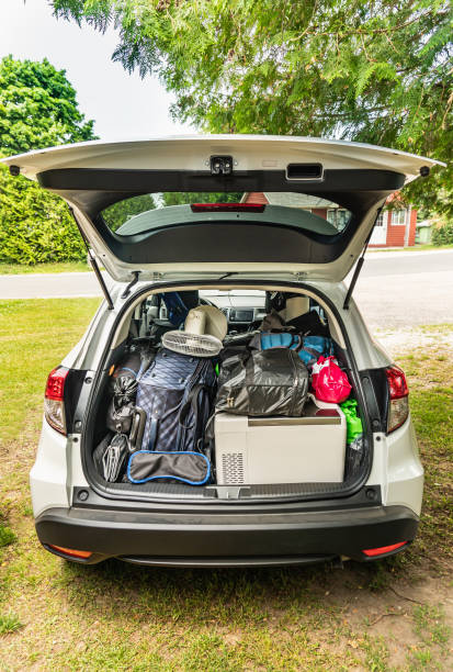 moderna auto suv con area di carico piena di bagagli per cottage o campeggio. viaggio di vacanza estiva o colpire il concetto di strada. turismo di viaggio ed esplorazione del tema della spedizione. - car rear view behind car trunk foto e immagini stock