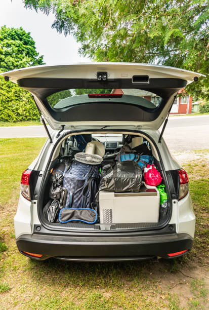 Modern suv car with cargo area full of luggage for cottage or camping. Summer vacation getaway trip or hit the road concept. Travel tourism and exploring expedition theme. stock photo