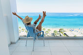 Young woman relaxing in chair on balcony of beachfront hotel or apartment