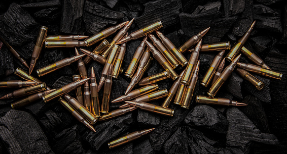 Cartridges for automatic carbine caliber .223 on charcoal. Ammunition for automatic and semi-automatic rifles. Dark background.