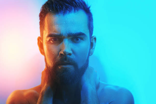 Portrait of handsome young man with wet face in blue and orange light