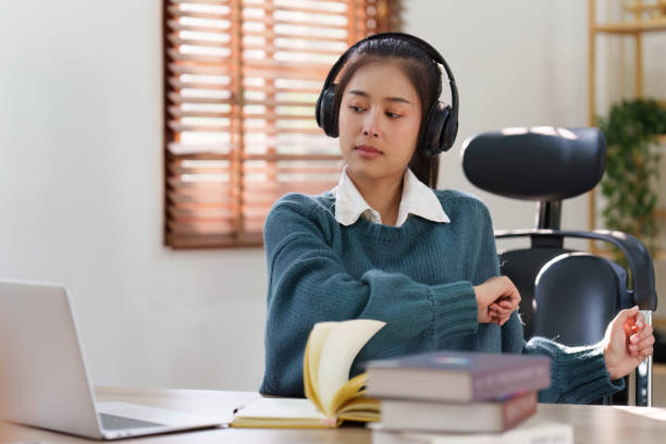istock Online education, e-learning. Asian woman relaxing after studying using a laptop, listening to online lecture, taking notes, online study at home 1486894899