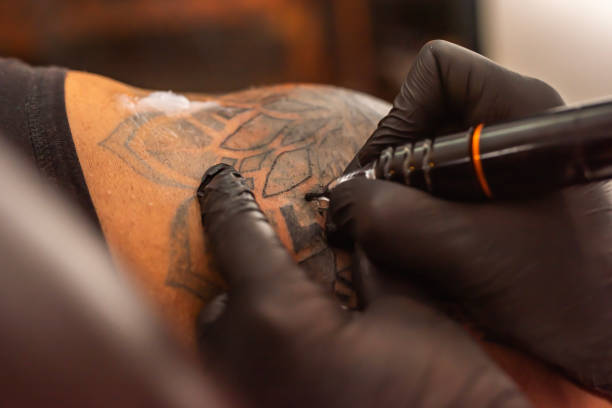 istock Professional tattooer doing tattoo on hand using tattoo machine in studio 1486896973