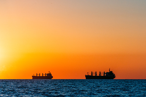 Silhouette of Large Cargo Ships at Sunset on the Pacific Ocean at Huntington Beach, California near Los Angeles