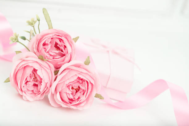 Three pink roses with ribbon and giftbox on the white table. Valentines day concept