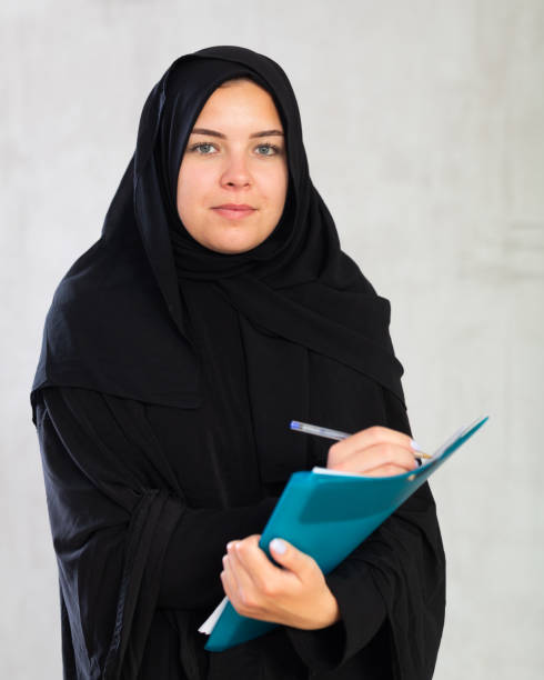 istock imperturbable girl in hijab holds several notebooks and writes important note in her diary 1486900384