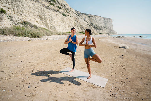 Young couple doing exercise together on the beach