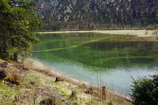 The Three Lakes area in spring. A shallow lake at the foot of the mountains. A lake in the Alps. Light grass around the lake. Alpine lake in spring.