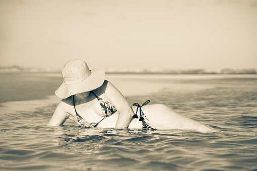 Mature woman relaxing in sea water. Taquari, Guaibim beach, Valenca, Bahia.