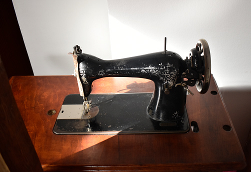 Close up of a vintage sewing machine on a wooden base.
