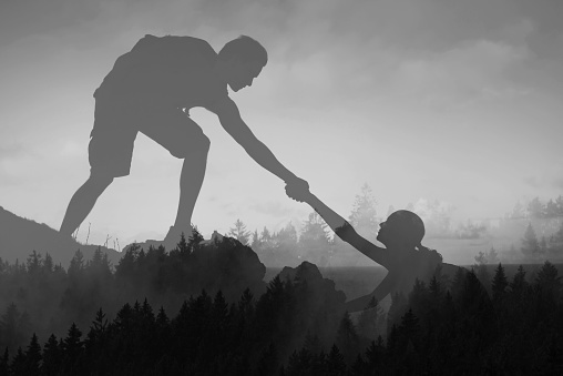 Giving friend a helping hand up a mountain