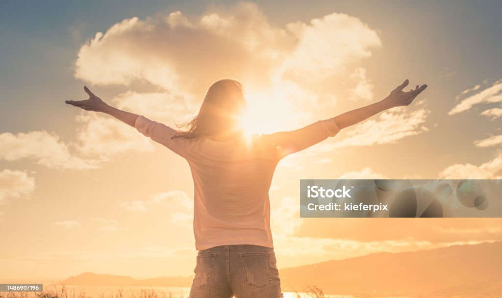 Young woman with hands up the morning sun light finding happiness, peace and hope in nature Young woman with hands up the sun light finding happiness, peace and hope Hope - Concept Stock Photo
