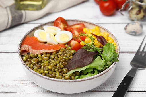 Bowl of salad with mung beans on white wooden table