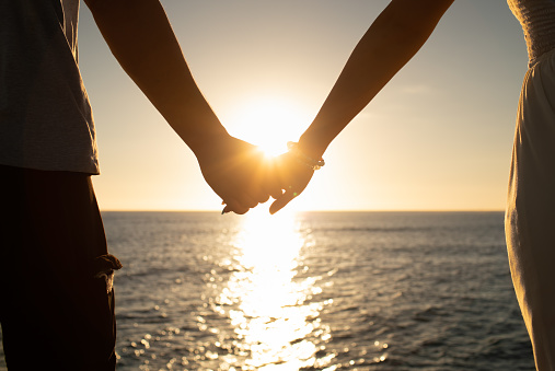 Closeup of couple holding hands watching the sunset