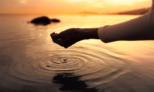 female hands touching calm water making gentle ripples