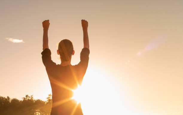 Young strong confident woman with fist up to sky stock photo
