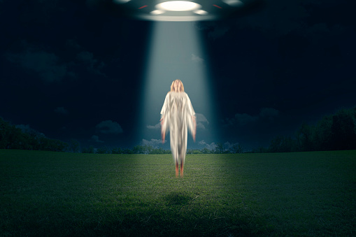 A conceptual image of a woman being abducted by an alien aircraft.