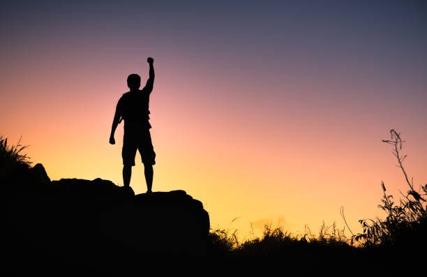 Man on top a mountain conquering adversity stock photo