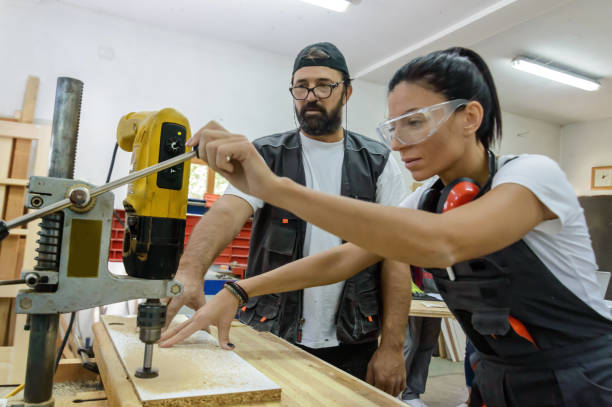 istock A Young Female Carpentry Worker is Working on Woodworks Using a Large Electric Drill with the Help of Coworker. 1486919068