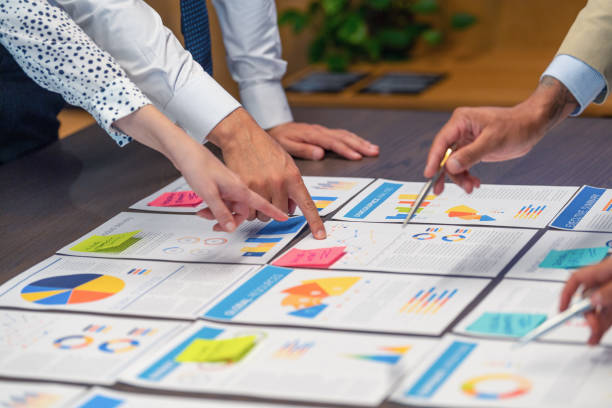 istock Paperwork and hands on a board room table at a business presentation or seminar. 1486919150