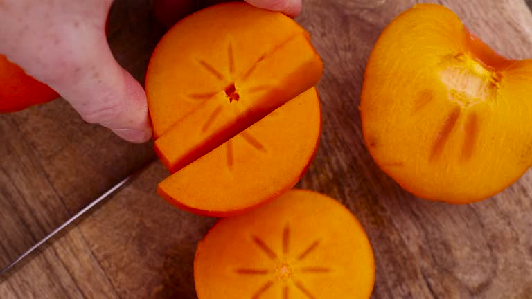 fresh ripe persimmon cut into pieces on a cutting board