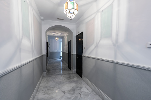 Entrance hallway to a residential block of flats with white marble flooring and half painted gray walls