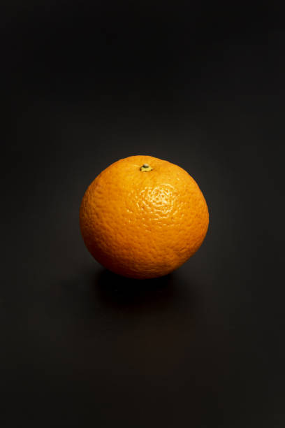 istock A lone orange with its rough skin on a black surface 1486926426