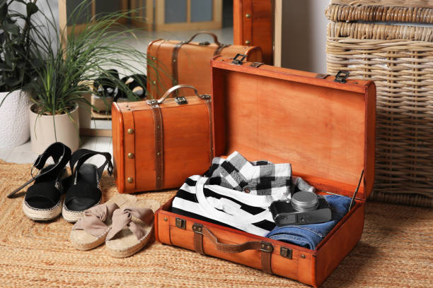 istock Open suitcase with folded clothes, accessories and shoes on carpet indoors 1486926858