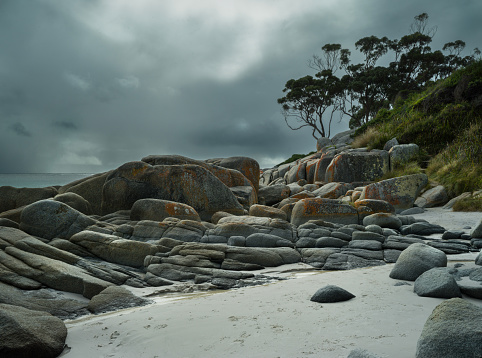 Dramatic sky over the Bay of Fires in Tasmania, red rocks and green blue sea