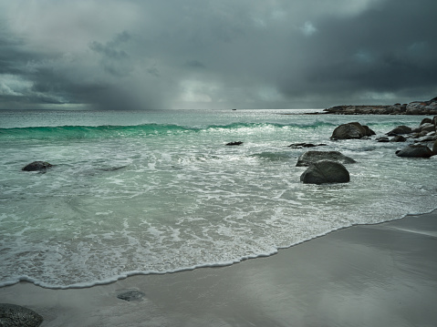 Dramatic sky over the Bay of Fires in Tasmania, red rocks and green blue sea