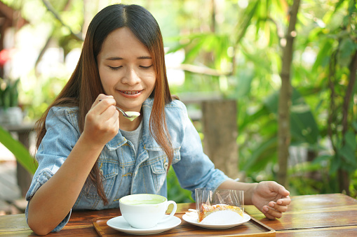 Woman using spoon to scoop hot green tea