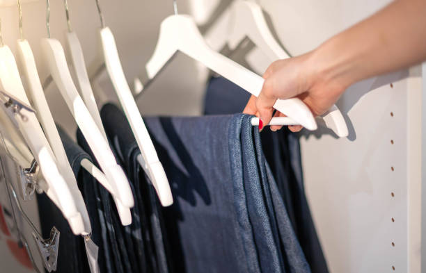 istock Female hand choosing clothes for checked pattern trouser on the rack in cloth shop at a department store. Check price, discount, and promotion of clothing products. 1486937842