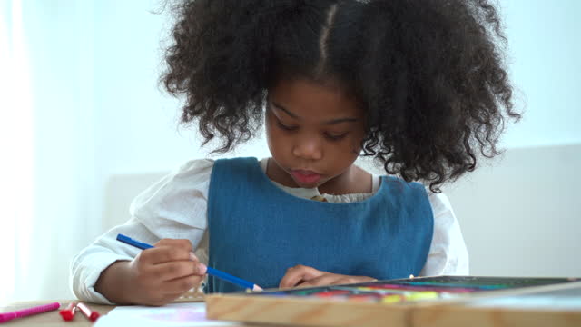 Little girl drawing and painting a picture.