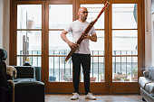 young latin man venezuelan musician in his living room standing playing the bassoon
