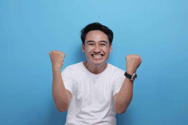 istock Happy Asian man shows winning gesture, celebrating victory 1486951652