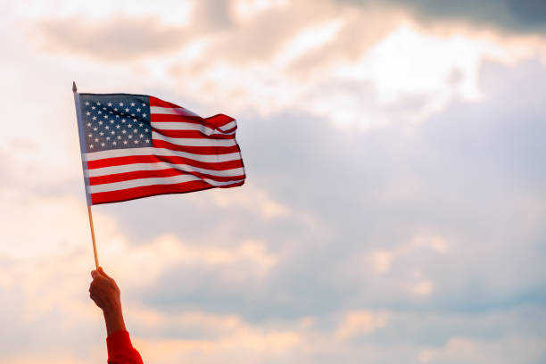hand waving the flag of the united stated of america - american flag flag usa sky imagens e fotografias de stock