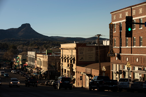 A photo of a typical small town main street in the United States of America. Features old brick buildings with specialty shops and restaurants. Decorated with spring flowers and American flags.