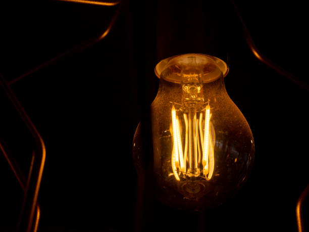 istock Vintage incandescent light bulb filament on black, close up shot 1486961121