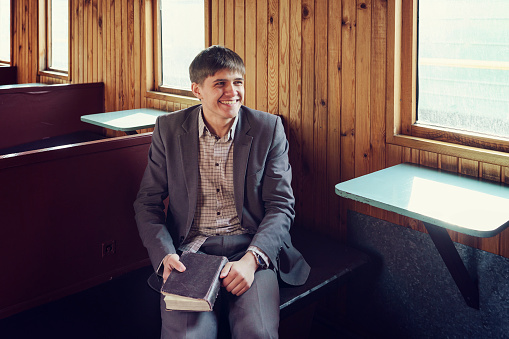 Portrait of CEO in front of her office. He is holding a folder, looking at the camera, smiling