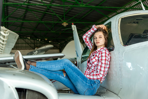 Young female pilot posing with her small plane.