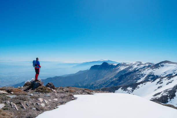 istock Successful senior mountain climber is celebrating his success and watching  the beautiful scenery of forest  and mountain range on the summit of a mountain 1486984466